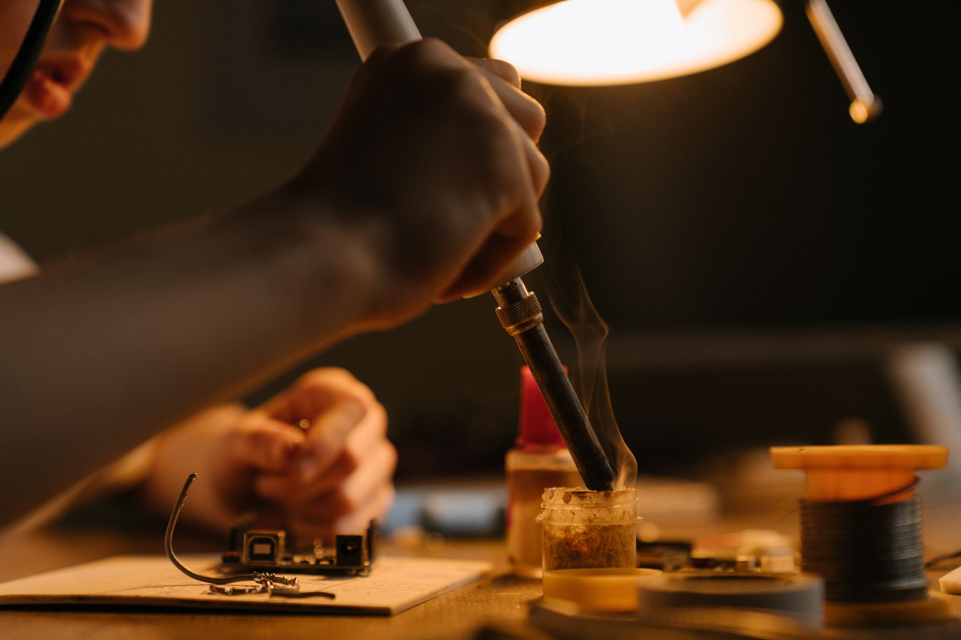 A builder soldering a board under a desk lamp